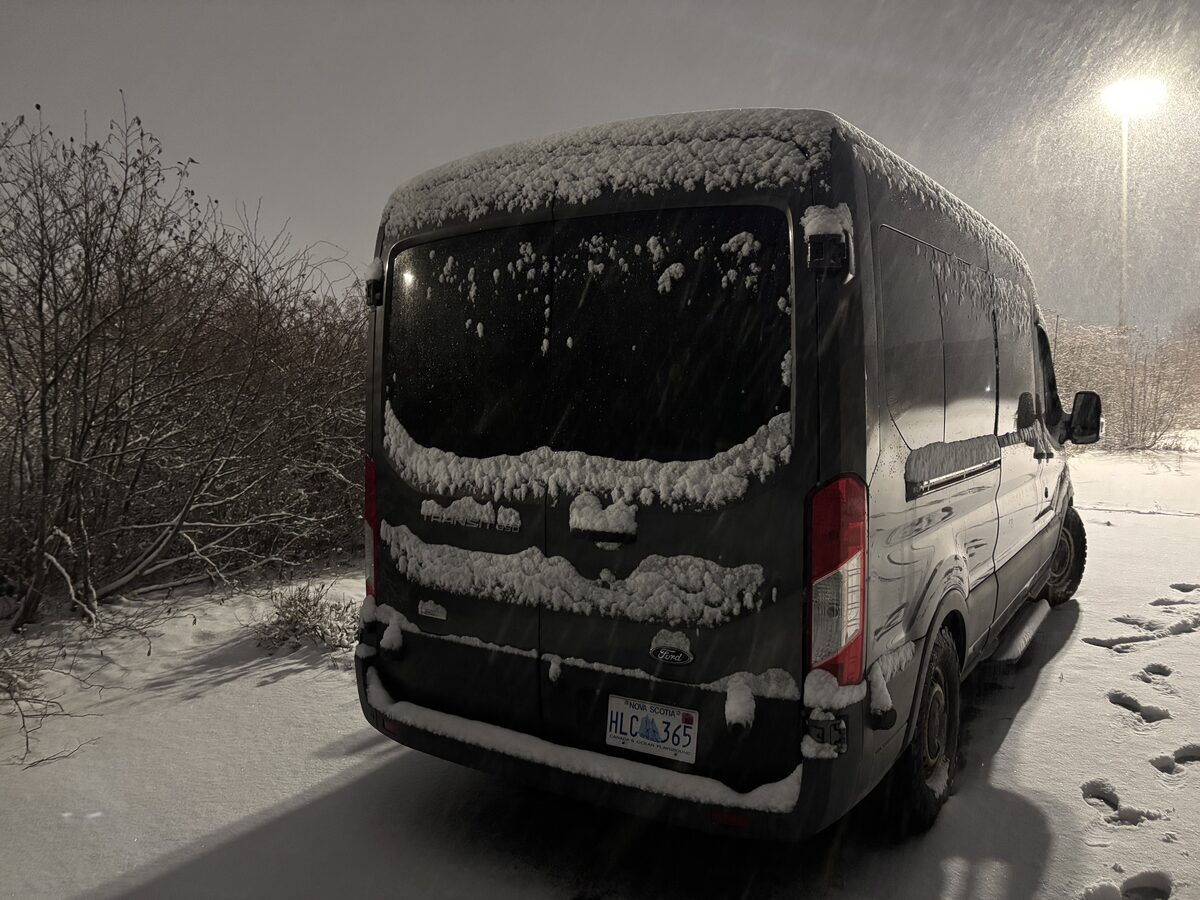 Rear access area during snowfall, relevant to gear storage, recovery tools, and wet-weather loading.